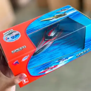Caja roja y azul con lancha de carreras a control remoto visible a través de ventana transparente.